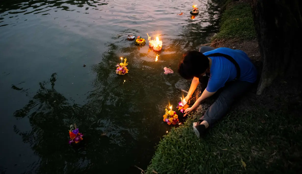 Seorang wanita Thailand melarung 'krathong' untuk merayakan festival Loy Krathong di sebuah danau di Bangkok, Kamis (22/11). Festival ini biasanya berlangsung pada akhir musim hujan, ketika bulan purnama menyala di langit pada November. (Jewel SAMAD/AFP)