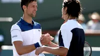 Petenis Serbia Novak Djokovic memberikan selamat kepada Taro Daniel asal Jepang setelah dikalahkan pada putaran kedua Indian Wells, Minggu (11/3/2018). (MATTHEW STOCKMAN / GETTY IMAGES NORTH AMERICA / AFP)