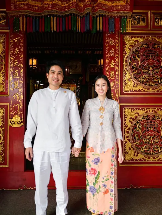 Saat foto bersama tunangannya, Nong Poy kembali memilih kebaya dan kain. Lengkap dengan aksesori bros dan perhiasan lain. [@poydtreechada]