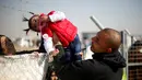 Seorang pria menyeberangkan anak perempuan melewati kawat berduri di kamp pengungsian Khazer, Irak (28/11). Mereka pergi meninggalkan daerah yang sebelumnya dikuasai kelompok militan ISIS untuk mengungsi ke tempat yang lebih aman. (Reuters/Mohammed Salem)