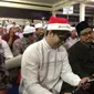 Pria bernama Alim memakai topi Santa Klaus berwarna merah putih lengkap dengan tulisan Merry Christmas saat Haul ke-7 Gus Dur. (Liputan6.com/Taufiqqurohman)