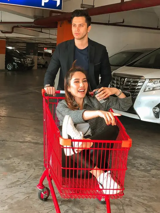 Seperti usai keluar dari mall. Keduanya pun sempatkan berpose dan berfoto di parkiran. Louise Anastasya pun duduk di atas troli sampi masuk ke dalamnya dengan memegang kopi. (Liputan6.com/IG/@louiseans)