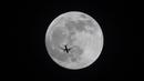 Sebuah pesawat terbang melewati bulan purnama di atas Basra, Irak, Minggu (15/5/2022). (AP Photo/Nabil al-Jurani)