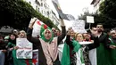 Demonstran memegang bendera dan spanduk saat berunjuk rasa di Aljir, Aljazair, Jumat (19/4). Demonstrasi sudah memasuki pekan ke kesembilan. (REUTERS/Ramzi Boudina)