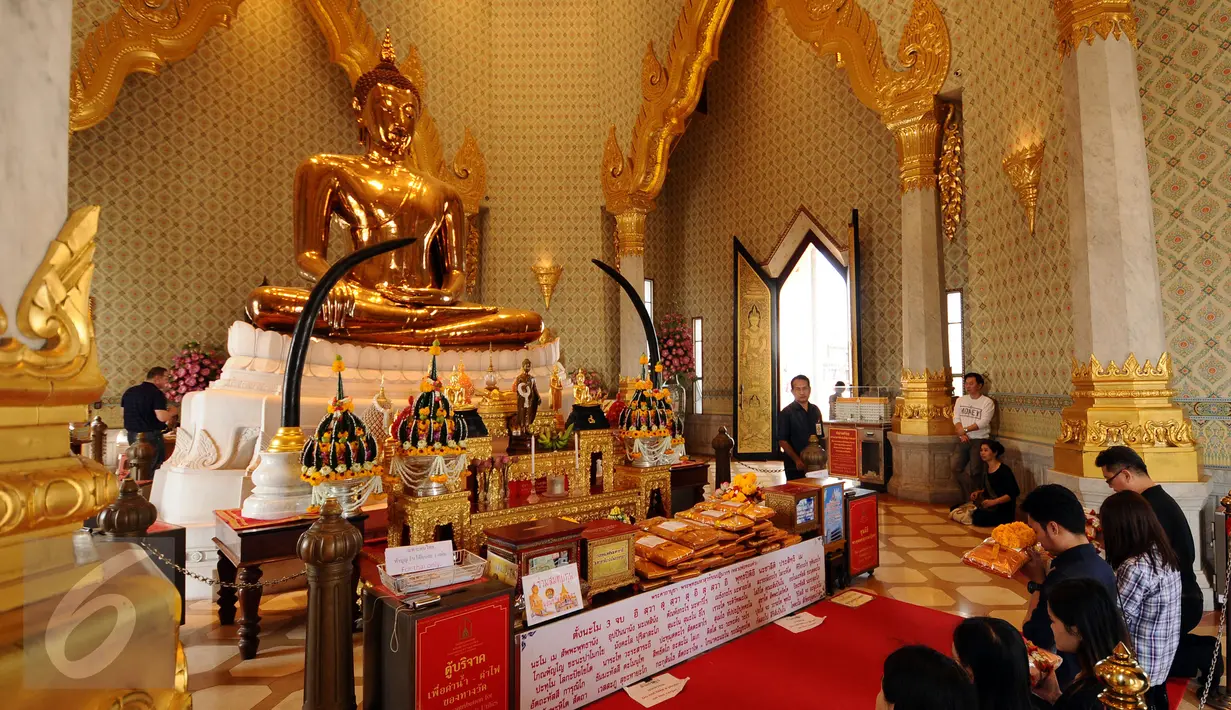 Pengunjung berdoa di depan Golden Budha di kota Bangkok, Thailand, Sabtu (17/12). Salah satu biksu yang ada di kuil tersebut memprediksi hasil laga final kedua Piala AFF 2016 antara Thailand melawan Indonesia. (Liputan6.com/Helmi Fithriansyah)