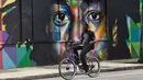 Seorang pria bersepeda melintas di depan mural karya seniman Brasil Kobra di kawasan Wynwood, Miami, Florida pada 28 September 2016. Goldman Properties menggelar pameran mural untuk merevitalisasi lingkungan. (AFP PHOTO / Rhona WISE)