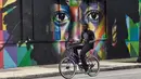 Seorang pria bersepeda melintas di depan mural karya seniman Brasil Kobra di kawasan Wynwood, Miami, Florida pada 28 September 2016. Goldman Properties menggelar pameran mural untuk merevitalisasi lingkungan. (AFP PHOTO / Rhona WISE)