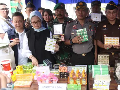 Kepala BPOM RI Penny K Lukito menunjukkan barang bukti kosmetik palsu di kawasan Tambora, Jakarta Barat, Selasa (15/5). Petugas menemukan 21 item produk jadi kosmetik ilegal, bahan baku, dan alat produksi. (Liputan6.com/Arya Manggala)