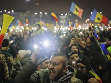 Pengunjuk rasa berkumpul di pusat Bucharest sambil melambai-lambaikan bendera, Rumania, Minggu (5/2). Mereka bersorak mendengar pengumuman yang dikeluarkan setelah unjuk rasa selama hampir 1 minggu. (AP Photo)