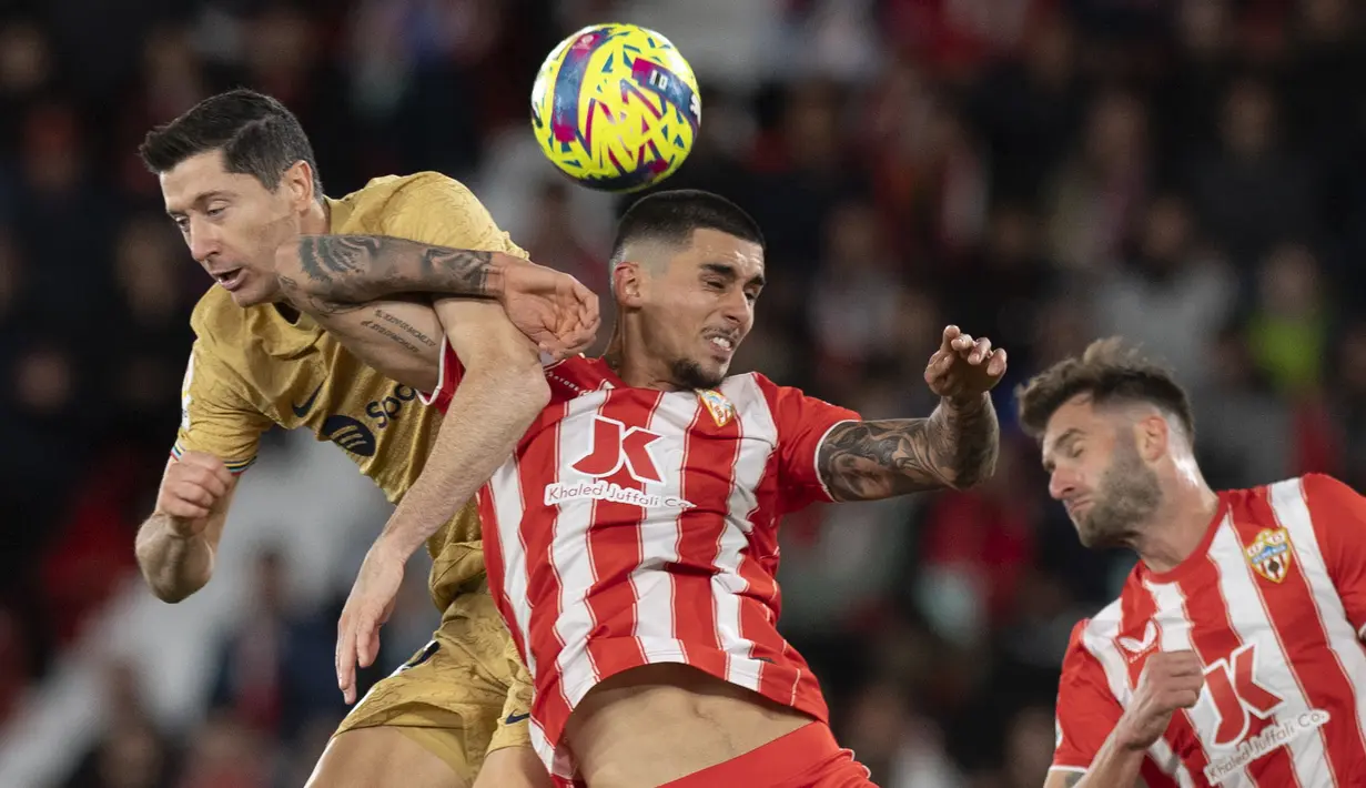 Pemain Barcelona, Robert Lewandowski (kiri) berebut bola dengan pemain Almeria Chumi pada laga lanjutan Liga Spanyol 2022/2023 yang berlangsung di Power House Stadium, Senin (27/02/2023) dini hari WIB. (AFP/Jorge Guerrero)