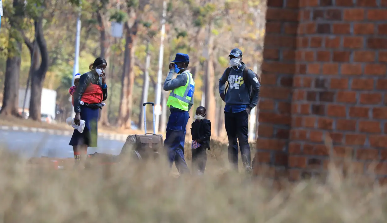 Petugas polisi mengenakan masker berbicara dengan seorang wanita di Harare (22/7/2020). Presiden Zimbabwe Emmerson Mnangagwa mengumumkan sederet kebijakan karantina lockdown, termasuk penerapan jam malam mulai pukul 18.00-06.00 waktu setempat, guna meredam lonjakan kasus COVID-19. (Xinhua/Wanda)