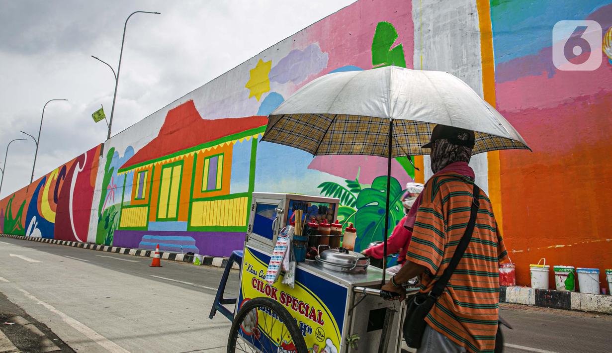 Seorang pedagang melintasi mural yang dibuat di Flyover Gaplek, Tangerang Selatan, Rabu (10/3/2021). Konsep muralnya adalah "Tangsel Membangun". (Liputan6.com/Faizal Fanani)