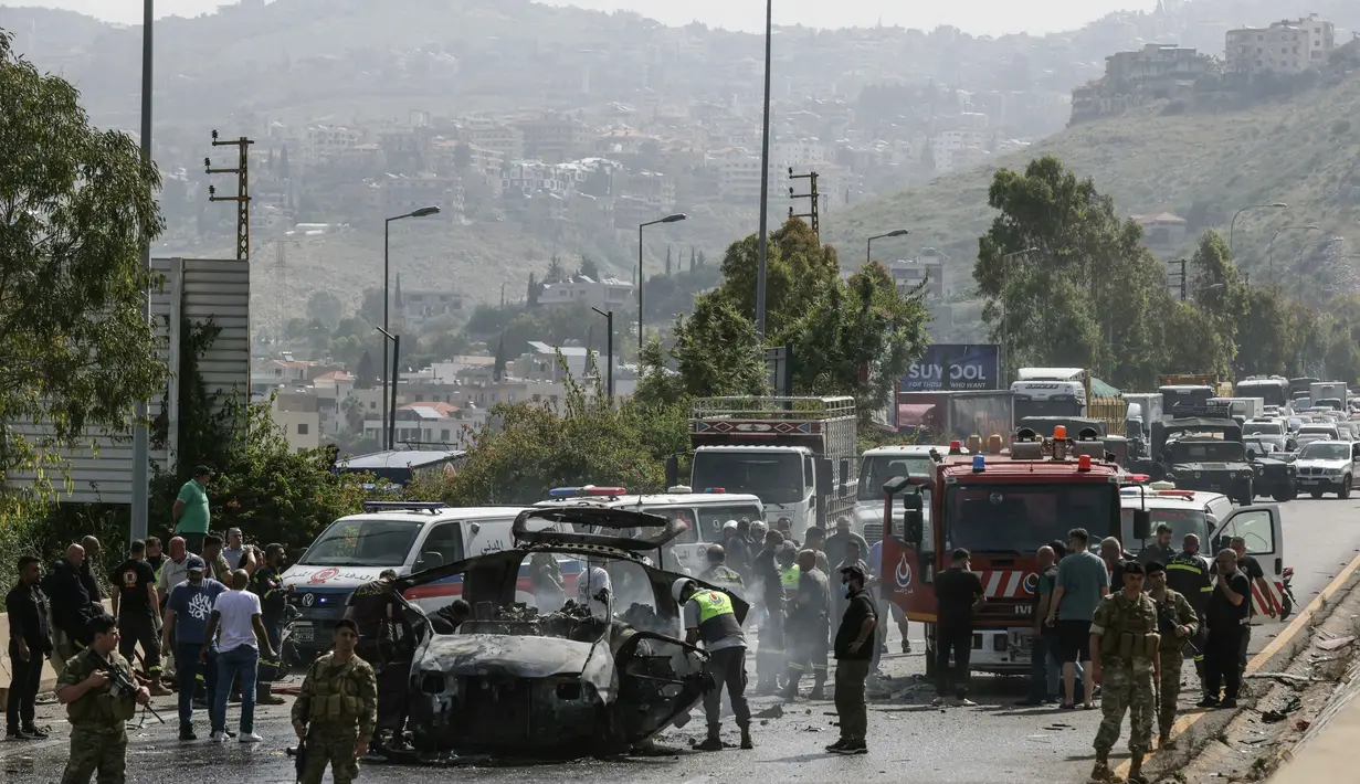 Petugas tanggap darurat bekerja di sekitar kendaraan yang menjadi sasaran serangan pesawat tak berawak Israel di jalan raya dekat kota Jiyeh, Selatan Beirut, pada Rabu 13 Mei 2026. (MAHMOUD ZAYYAT/AFP)