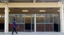 Pewarta melintas di depan istal di kawasan Jakarta International Equestrian Park Pulomas, Jakarta, Kamis (2/8). JIEPP akan menjadi venue tiga cabang equestrian Asian Games 2018. (Liputan6.com/Helmi Fithriansyah)