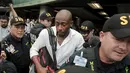 Pelatih timnas Kosta Rika, Paulo Wanchope (tengah) dikawal polisi saat tiba di bandara internasional Juan Santamaria, Alajuela 12 Agustus 2015. Wanchope terlibat dalam perkelahian saat kualifikasi Olimpiade melawan Panama. (REUTERS/Juan Carlos Ulate)