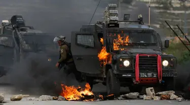 Tentara Israel meninggalkan kendaraan yang terbakar oleh lemparan bom molotov warga Palestina di pinggiran Kota Ramallah, Tepi Barat, Rabu (27/3). Bentrokan ini sebagai bentuk protes terhadap tahanan Palestina yang berada di Israel. (AP Photo/Majdi Mohammed)