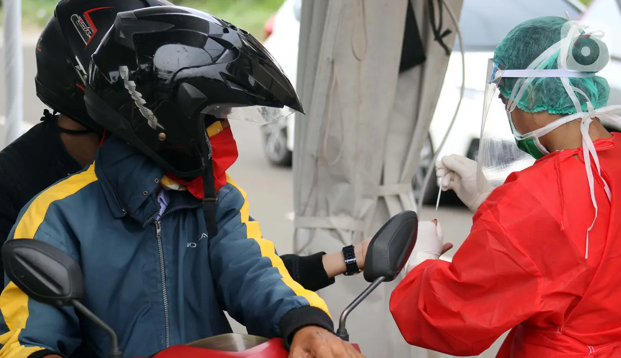 Petugas medis mengambil sample darah saat tes cepat diagnosa COVID-19 yang digelar secara drive thru di titik pengecekan Terminal Jatijajar, Depok, Jawa Barat, Kamis (28/5/2020). Tes cepat ini hasilnya langsung dikonfirmasi dan dilaksanakan hingga Jumat (29/5). (Liputan6.com/Helmi Fithriansyah)