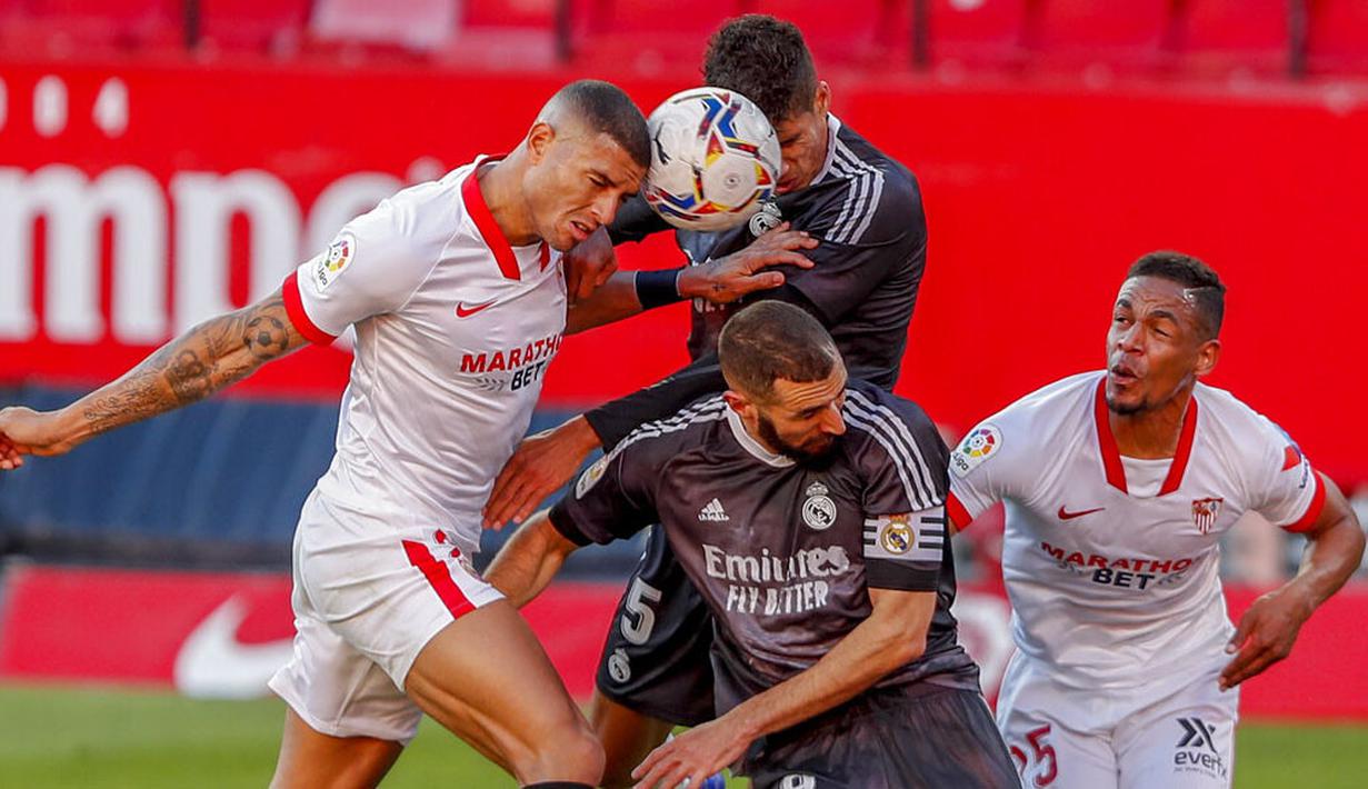 Bek Real Madrid, Raphael Varane, berebut bola dengan pemain Sevilla, Diego Carlos, pada laga Liga Spanyol di Stadion Ramon Sanchez Pizjuan, Minggu (6/12/2020). Real Madrid menang dengan skor 1-0. (AP/Angel Fernandez)