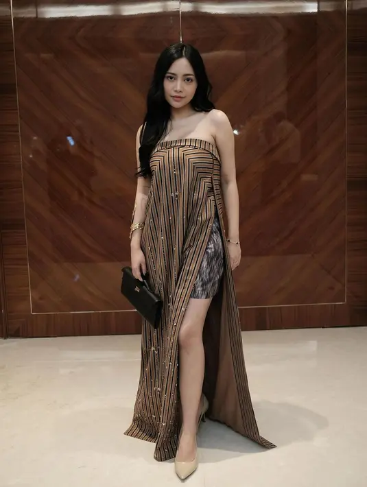 Rachel Vennya kenakan strapless dress lurik dengan detail slit yang tinggi. Sebagai inner, ia kenakan celana pendek lurik hitam dengan heels nude dan clutch Hermes [@rachelvennya]