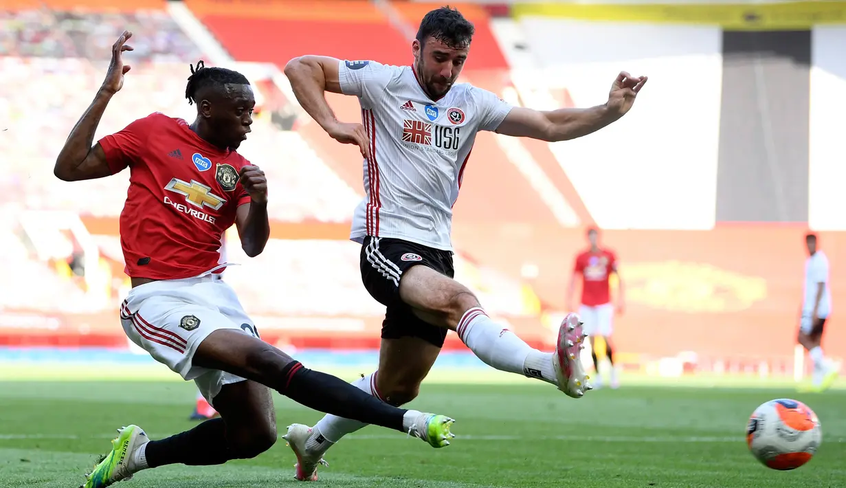 Bek Manchester United, Aaron Wan-Bissaka berusaha mengumpan bola dari kawalan pemain Sheffield United, Enda Stevens pada pertandingan lanjutan Liga Inggris di Old Trafford di Manchester, Inggris (24/6/2020). MU menang telak 3-0 atas Sheffield United. (Michael Regan / Pool via AP)