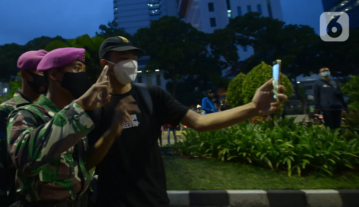 Seorang pendemo berselfie dengan anggota Marinir saat aksi menolak Omnibus Law UU Cipta Kerja di kawasan Patung Kuda, Jakarta, Selasa (20/10/2020).  Anggota Marinir membubarkan dan mengawal pulang massa pendemo  ke rumah masing-masing. (merdeka.com/Imam Buhori)