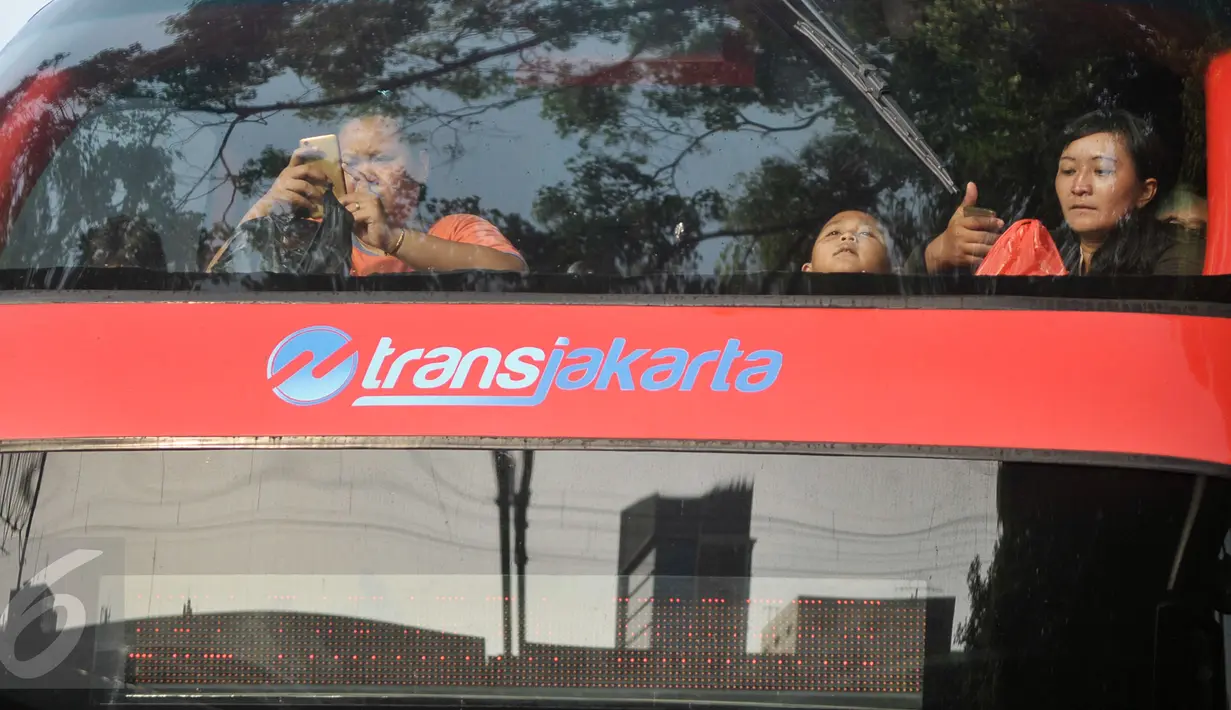 Penumpang menaiki bus tingkat wisata di depan halte Masjid Istiqlal, Jakarta, Minggu (30/4). Warga memanfaatkan hari libur panjang mereka dengan berkeliling Jakarta menggunakan bus tingkat ini secara gratis. (Liputan6.com/Yoppy Renato)