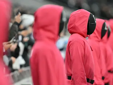 Orang-orang berpakaian seperti penjaga Squid Games dengan berdiri di area penonton selama pertandingan lanjutan Liga Inggris 2024/2025 antara Tottenham Hotspur melawan Liverpool di Stadion Tottenham Hotspur, London, Inggris Minggu (22/12/2024). Seperti diketahui, aksi tersebut ternyata merupakan promo musim kedua serial Korea Selatan tersebut. (AFP/Glyn Kirk)