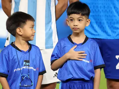 Cucu Presiden RI Joko Widodo, Jan Ethes (kanan) saat menjadi player escort pemain Timnas Argentina pada laga FIFA Matchday melawan Timnas Indonesia di Stadion Utama Gelora Bung Karno (SUGBK), Senayan, Jakarta, Senin (19/06/2023). (Bola.com/Bagaskara Lazuardi)