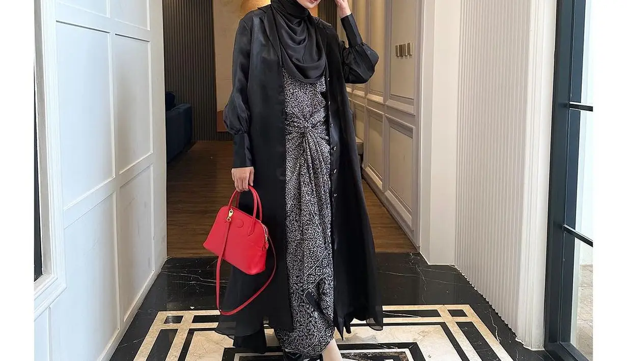 Shireen pilih kenakan twisted tunik dan long shirt satin hitam yang dipadukan hijab senada. Hand bag yang dijinjingnya jadi sentuhan kontras. [@shireensungkar]