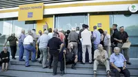 Sejumlah orang menunggu di pintu masuk Bank Piraeus di kota Iraklio, Yunani (20/7/2015). Pembukaan bank-bank di Yunani dilakukan usai Bank Sentral Eropa memberikan bantuan dana darurat senilai 900 juta euro. (REUTERS/Stefanos Rapanis) 