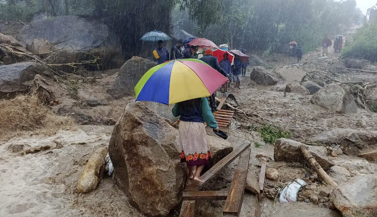 Orang-orang berjalan melintasi jembatan darurat di atas air banjir di Blantyre pada 14 Maret 2023, yang disebabkan oleh hujan lebat setelah mendaratnya topan Freddy. Topan Freddy, yang membawa angin kencang dan hujan deras, menewaskan lebih dari 100 orang di Malawi dan Mozambik saat kembali ke daratan Afrika bagian selatan, kata pihak berwenang pada 13 Maret 2023. (AFP/Jack McBrams)