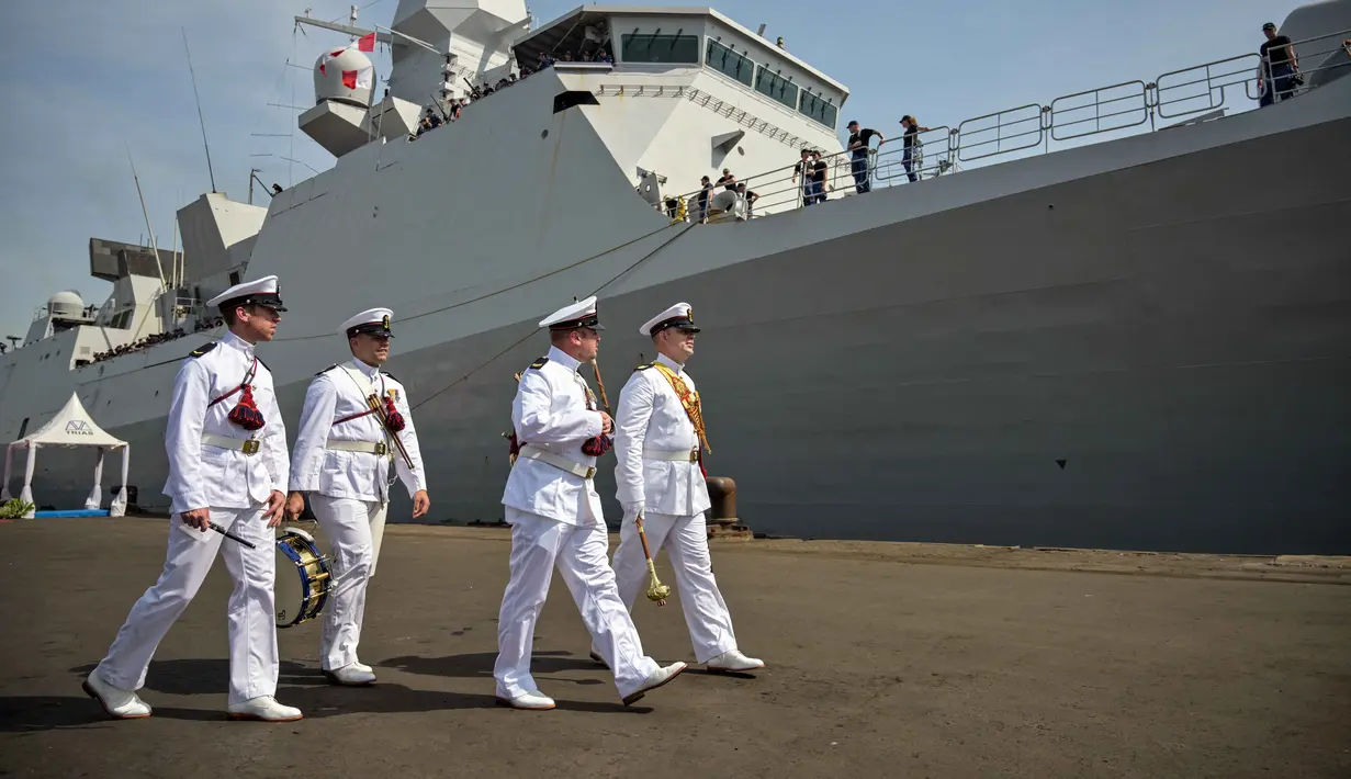 Para anggota Orkestra Marinir Belanda berjalan di samping kapal perang HNLMS De Ruyter di pelabuhan Tanjung Perak, Surabaya, Jawa Timur pada Kamis 14 Mei 2026. (JUNI KRISWANTO/AFP)