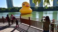 Orang-orang melihat bebek karet kuning raksasa yang mengapung di Danau Seokchon di Seoul pada 14 Oktober 2014. (JUNG YEON-JE / AFP)