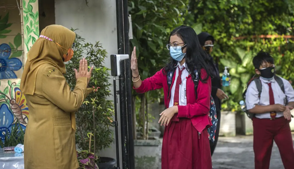 Seorang siswa menjalani pemeriksaan suhu tubuh saat memasuki sekolah sebelum mengikuti pembelajaran tatap muka (PTM) di sebuah sekolah di Surabaya, Jawa Timur, Senin (6/9/2021). Pemerintah kembali membuka sekolah di tengah pandemi COVID-19. (JUNI KRISWANTO/AFP)