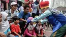 Badut yang tergabung dalam Aku Badut Indonesia mengajak bermain seorang anak saat car free day di Bunderan HI, Jakarta, Minggu (9/12). Aksi tersebut bentuk kampanye positif bertujuan mengajak masyarakat peduli terhadap sesama. (Liputan6.com/Faizal Fanani)