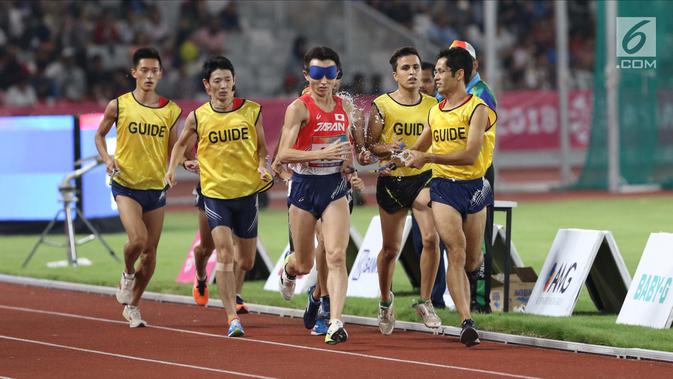 Pelari 5000 meter putra kategori T11 Asian Para Games 2018 saat laga final di SUGBK, Jakarta, Jumat (12/10). Tugas pemandu kategori T11 adalah mendampingi pelari utama mengarahkan kakinya agar bisa melaju cepat. (Liputan6.com/Helmi Fithriansyah)