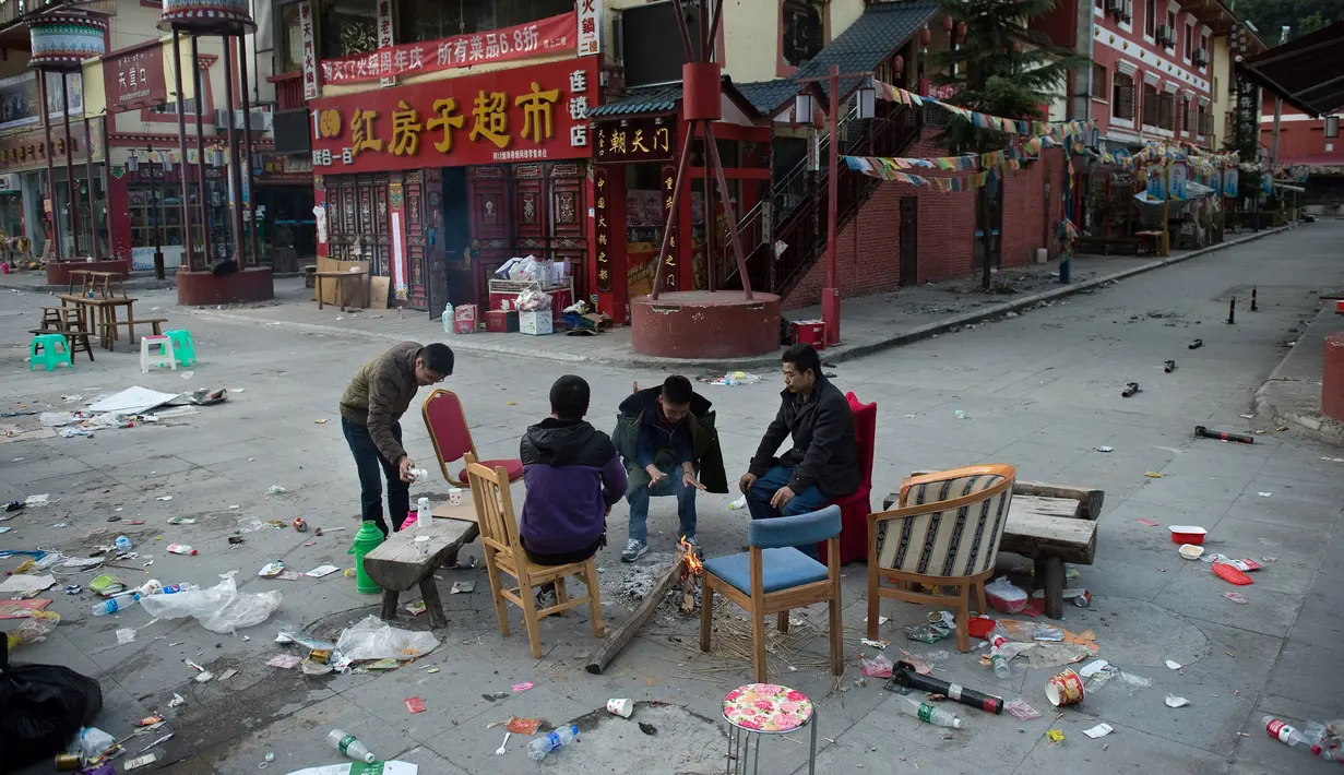 Sejumlah orang bersantai di sebuah jalan di Zhangzha, provinsi Sichuan, China barat daya, Kamis (10/8). Ratusan warga memilih menghabiskan malam di luar rumah setelah gempa 6,5 SR mengguncang wilayah itu dan menewaskan belasan orang (Nicolas ASFOURI/AFP)