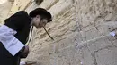 Pria Yahudi Ultra-Ortodoks berdoa di Tembok Barat di Kota Tua Yerusalem (30/3/2022). Pembersihan sebagai persiapan untuk liburan Paskah Yahudi yang akan datang. (AFP/Hazem Bader)