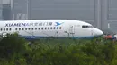 Petugas melihat pesawat milik XiamenAir yang tergelincir dari landasan di bandara internasional Manila, Filipina, Kamis (16/8). Insiden ini sempat memaksa penutupan sebagian Bandara Manila, khususnya landasan utama. (AFP/TED ALJIBE)