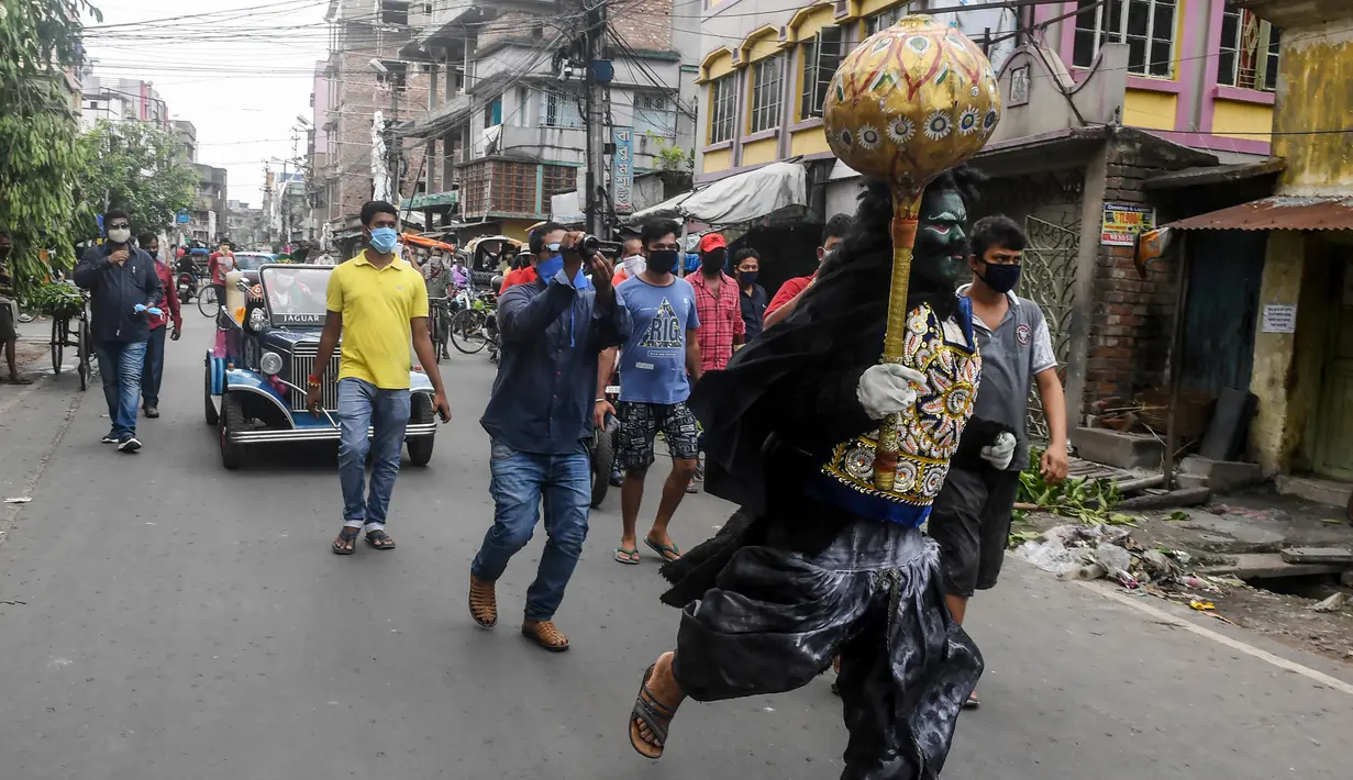 Seorang pria berkostum dewa kematian Yamaraj berlari keliling mencari warga yang masih berkeliaran tanpa masker di tengah lockdown di Kolkata, India (24/4/2020). Dalam aksinya, pria tersebut memberikan imbauan kepada warga agar memakai masker di tengah wabah virus corona. (AFP/Dibyangshu Sarkar)