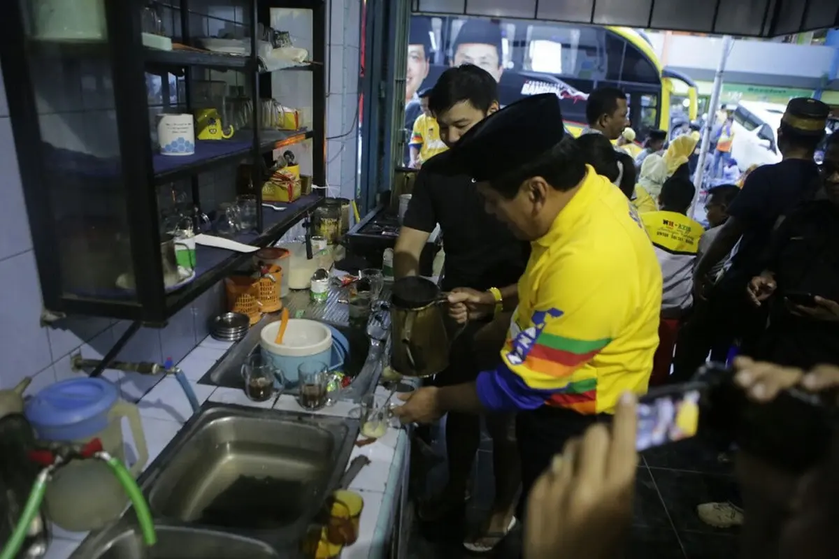 Cagub Sulsel, Nurdin Halid berlagak sebagai peracik kopi melayani pengunjung salah satu warkop di Kabupaten Soppeng, Sulsel (Liputan6.com/ Eka Hakim)
