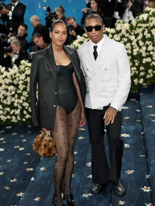 Helen Lasichanh istri Pharell William mengenakan Louis Vuitton, dari jaket kulit senada dengan jumpsuit pantless dipadukan stocking hitam motif LV. [dok. Louis Vuitton]
