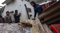 Seorang pemuda menyelamatkan roti dari sebuah rumah yang rusak, setelah pengeboman Israel di Rafah, Jalur Gaza selatan pada 25 Februari 2024. (SAID KHATIB/AFP)
