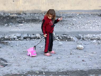 Seorang anak perempuan Palestina menarik mainannya di jalan yang dipenuhi puing-puing di Jabalia, Jalur Gaza utara pada 20 November 2024. (Omar AL-QATTAA/AFP)