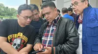 Anggota Komisi VII DPR Muhammad Nasir (pegang HP) usai melaporkan personel Polres Indragiri Hilir ke Propam Polda Riau terkait SP3 kasus penyelewengan BBM bersubsidi. (Liputan6.com/M Syukur)