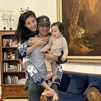 Dalam potret terbaru, Olivia yang mengenakan baju two pieces bermotif sedang digendong oleh sang suami yang mengenakan kaos abu-abunya. Si kecil tampil dengan jumpsuit cokelat. Credit: Instagram (@oliviazallianty)