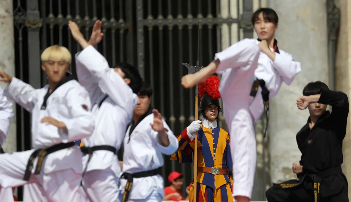Atlet Taekwondo dari Korea Selatan melakukan gerakan saat tampil di depan Paus Fransiskus saat pertemuan umum mingguan di Lapangan Santo Petrus, Vatikan (30/5). (AP Photo/Gregorio Borgia)