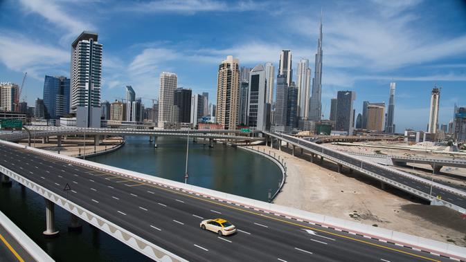 LOCKDOWN DUBAI: Sebuah taksi melintasi jalan raya yang sepi dekat Burj Khalifa di Dubai, Uni Emirat Arab, Senin (6/4/2020). Pemerintah Dubai memberlakukan lockdown selama dua pekan untuk mengantisipasi penyebaran virus corona COVID-19. (AP Photo/Jon Gambrell)