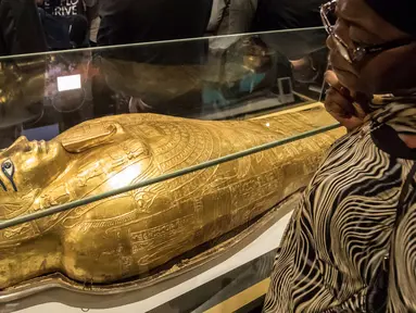 Seorang wanita memperhatikan peti mati emas mumi Nedjemankh yang dipajang di Museum Nasional Peradaban Mesir, Kairo, Selasa (1/10/2019). Nedjemankh merupakan seorang imam di zaman Ptolemeus, sekitar 2.000 tahun lalu. (Khaled DESOUKI/AFP)