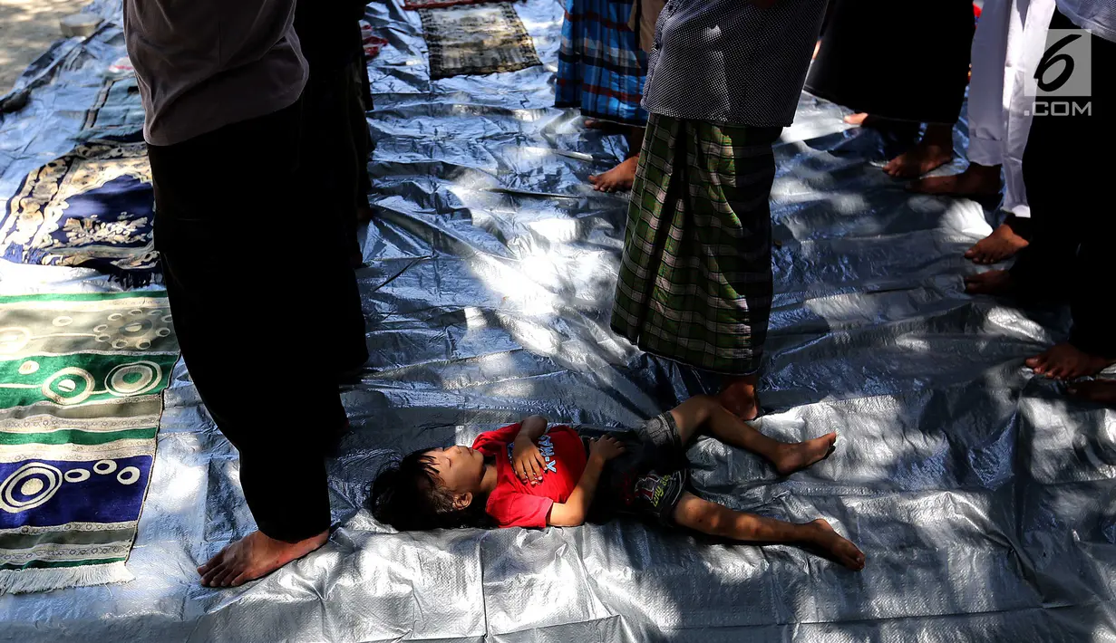 Seorang anak tertidur lelap saat salat Jumat pascagempa dan tsunami di Lapangan Masjid Agung Daru Salam, Palu, Jumat (5/10). Para pengungsi menggelar salat jumat pertama pascagempa bumi dan tsunami. (Liputan6.com/Fery Pradolo)